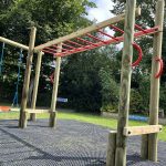 Close-up of red monkey ladder and blue rope swing logs